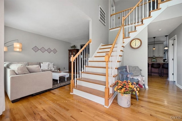 staircase with baseboards, a towering ceiling, and wood finished floors