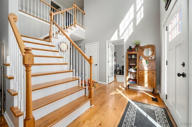 foyer featuring stairway, baseboards, wood finished floors, and a towering ceiling