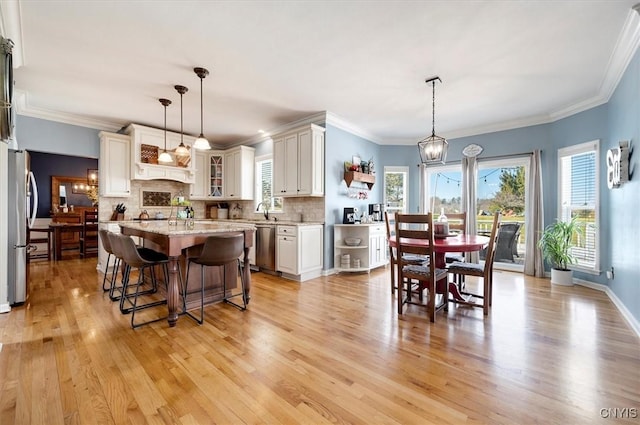 dining room featuring a notable chandelier, light wood-style flooring, crown molding, and baseboards