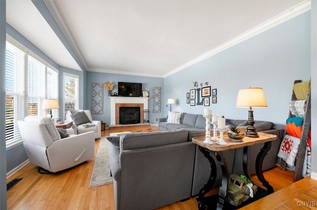 living area with visible vents, crown molding, light wood finished floors, baseboards, and a brick fireplace