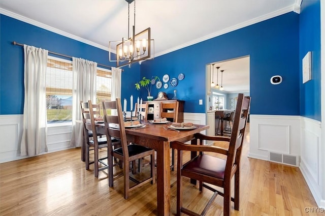 dining area featuring visible vents, a notable chandelier, wood finished floors, and crown molding