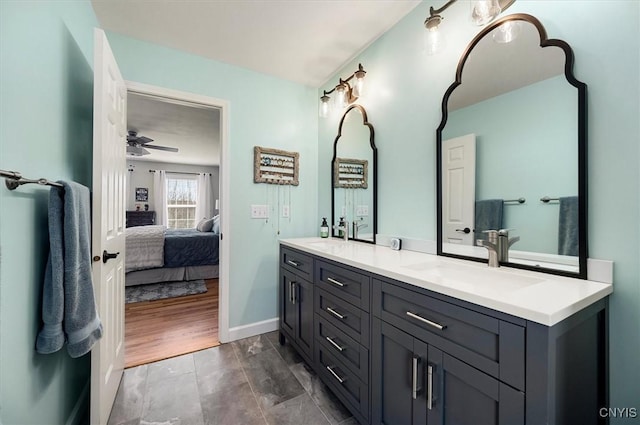 full bathroom featuring a sink, connected bathroom, double vanity, baseboards, and ceiling fan