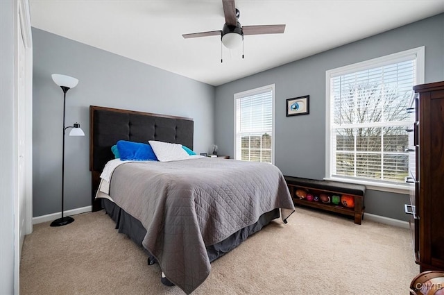 bedroom featuring light carpet, a ceiling fan, and baseboards