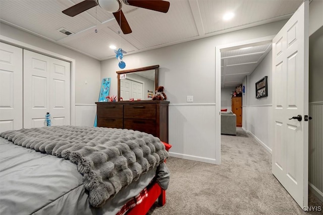 carpeted bedroom with a wainscoted wall, a ceiling fan, visible vents, and a closet