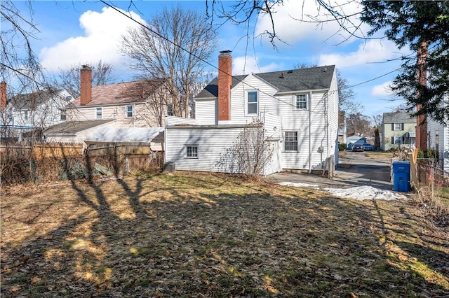 rear view of property featuring a chimney, a patio, and fence