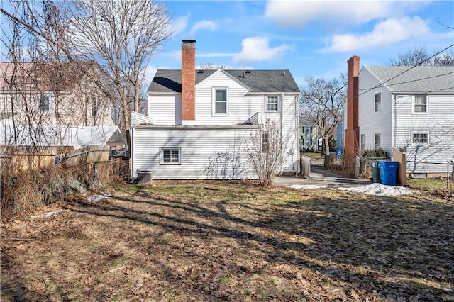 rear view of house featuring a patio area, a chimney, and fence