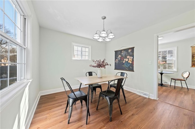 dining area featuring light wood finished floors, visible vents, an inviting chandelier, and baseboards