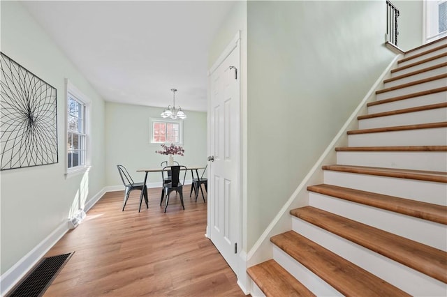 stairway with visible vents, baseboards, wood finished floors, and a chandelier