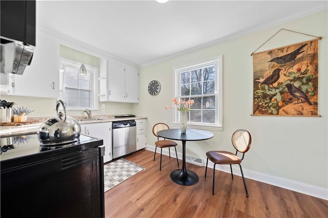 kitchen featuring light wood-style flooring, dishwasher, light countertops, and crown molding