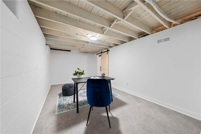 interior space with a barn door, concrete block wall, visible vents, and concrete flooring