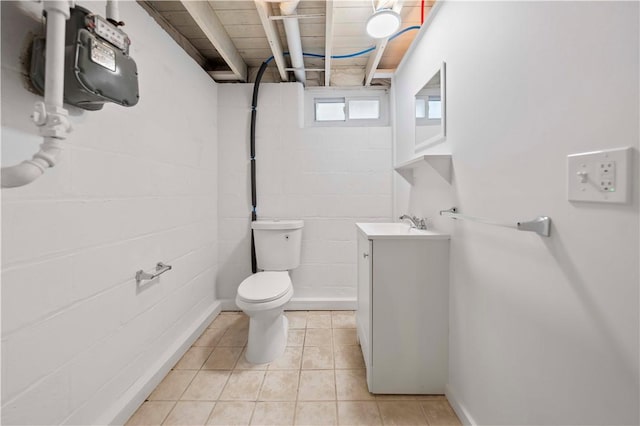 bathroom featuring vanity, tile patterned floors, concrete block wall, and toilet