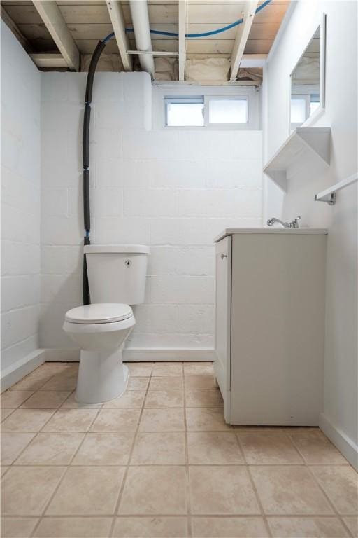 bathroom with tile patterned floors, toilet, and concrete block wall