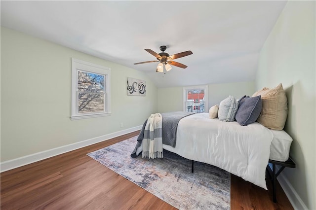 bedroom featuring lofted ceiling, wood finished floors, baseboards, and ceiling fan