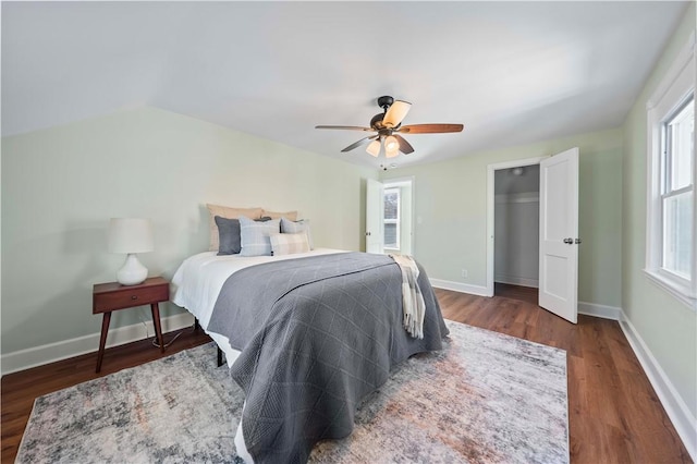 bedroom with ceiling fan, baseboards, wood finished floors, and vaulted ceiling