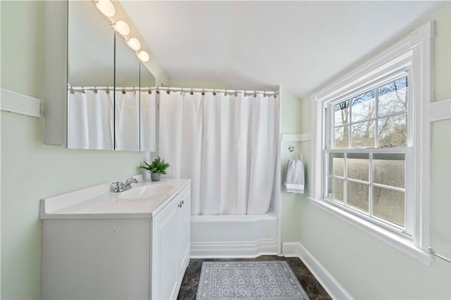 full bathroom featuring vanity, vaulted ceiling, baseboards, and shower / bath combo