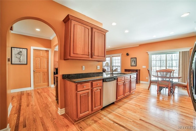 kitchen featuring stainless steel dishwasher, brown cabinetry, and arched walkways