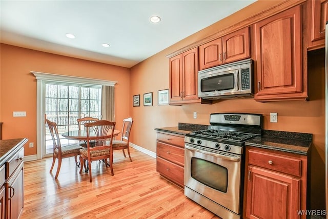 kitchen with baseboards, brown cabinets, appliances with stainless steel finishes, and light wood-type flooring