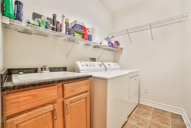 clothes washing area featuring light tile patterned floors, baseboards, laundry area, a sink, and washer and clothes dryer