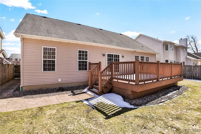 rear view of house with a yard, a deck, roof with shingles, and fence private yard