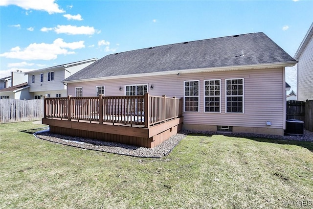 back of property with a deck, a yard, a fenced backyard, and a shingled roof