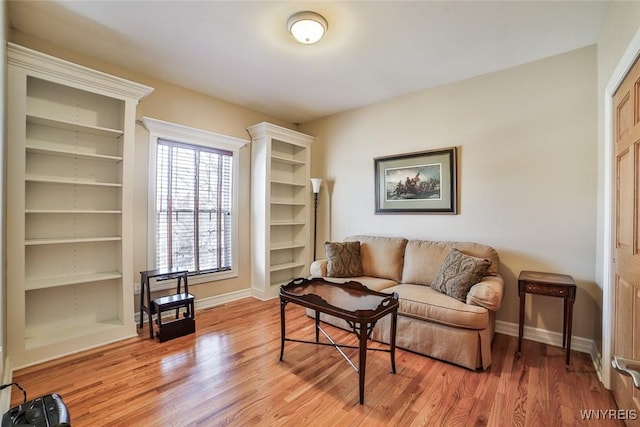 living area with light wood finished floors, built in shelves, and baseboards