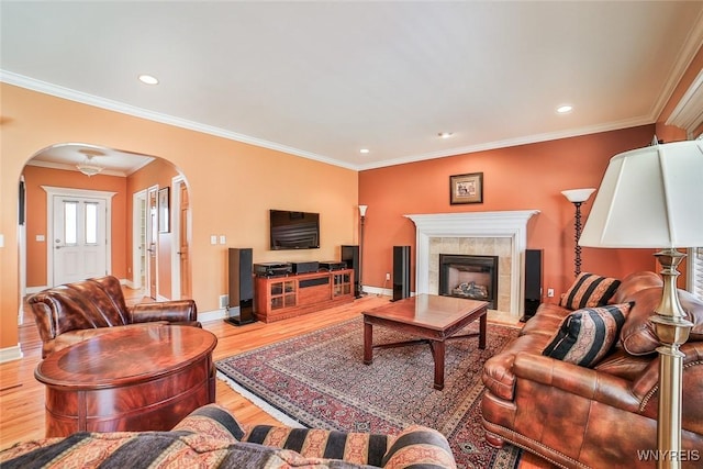 living area with wood finished floors, baseboards, recessed lighting, arched walkways, and ornamental molding