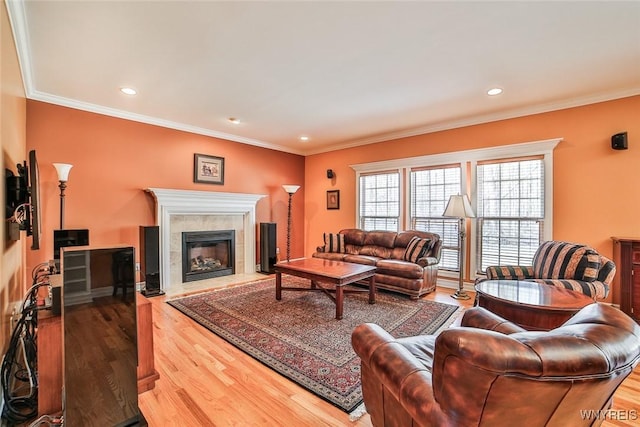 living area with recessed lighting, wood finished floors, a tile fireplace, and ornamental molding