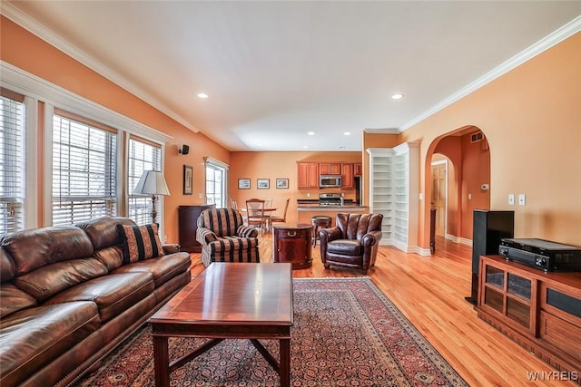 living area featuring light wood-style flooring, ornamental molding, recessed lighting, arched walkways, and baseboards