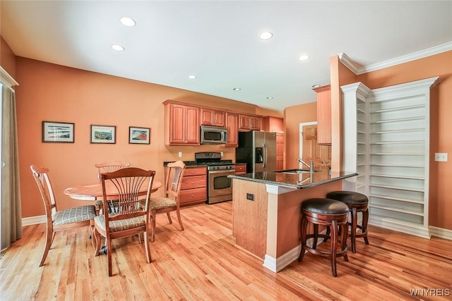 kitchen featuring a breakfast bar, recessed lighting, a peninsula, appliances with stainless steel finishes, and light wood finished floors