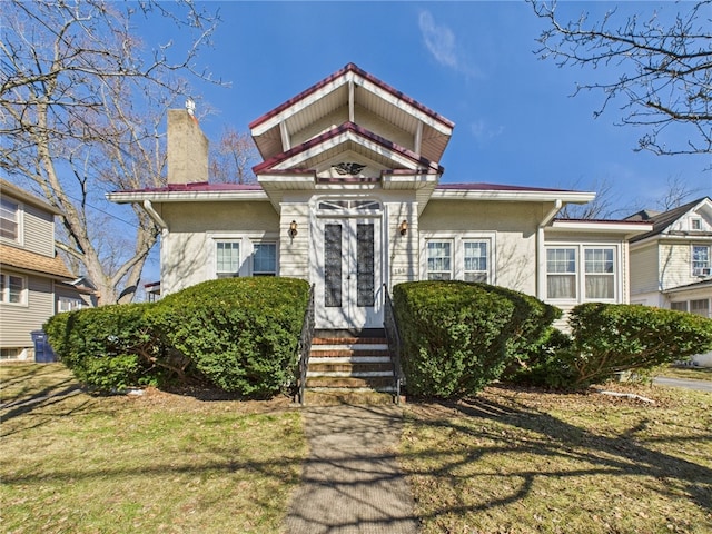 view of front of house featuring a front lawn, stucco siding, and a chimney