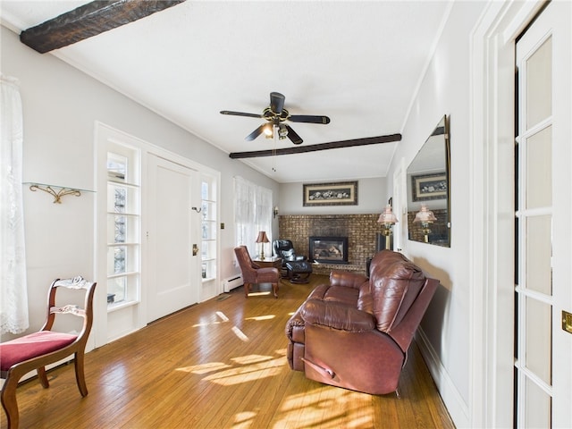 living room featuring a baseboard radiator, beam ceiling, a brick fireplace, and wood finished floors