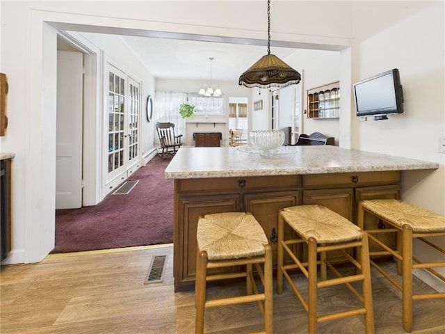 kitchen with visible vents, pendant lighting, light countertops, wood finished floors, and a notable chandelier