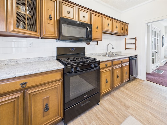 kitchen featuring light wood-type flooring, black appliances, ornamental molding, a sink, and brown cabinetry