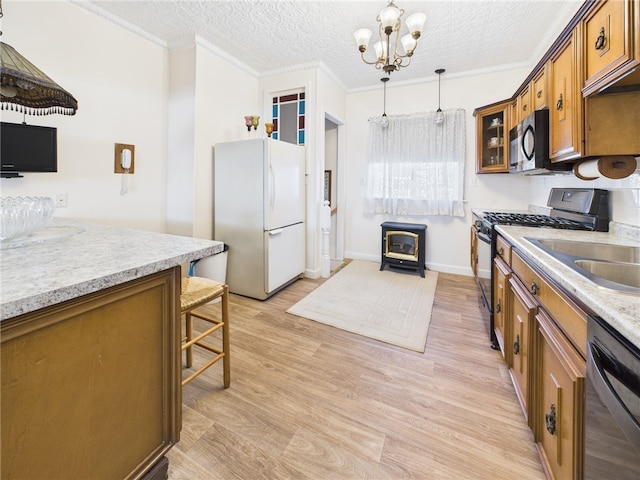 kitchen with light wood finished floors, a wood stove, stainless steel appliances, crown molding, and brown cabinets