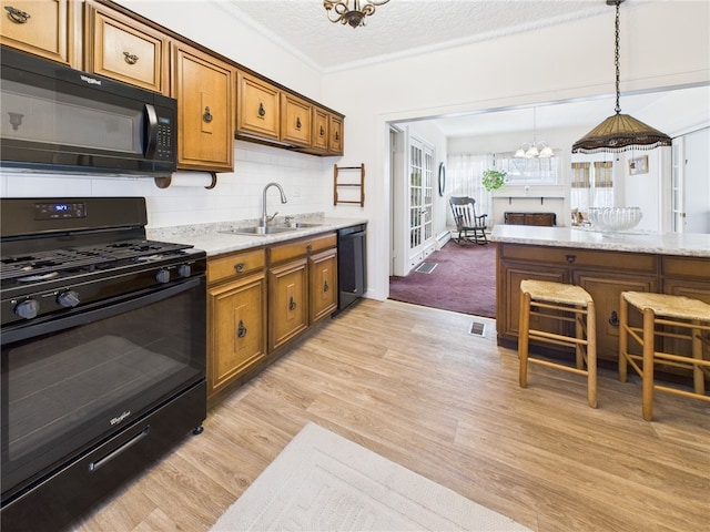 kitchen featuring black appliances, a sink, backsplash, light wood-style floors, and brown cabinetry