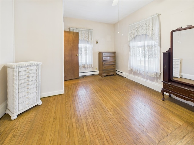 interior space with hardwood / wood-style flooring, baseboards, baseboard heating, and ceiling fan