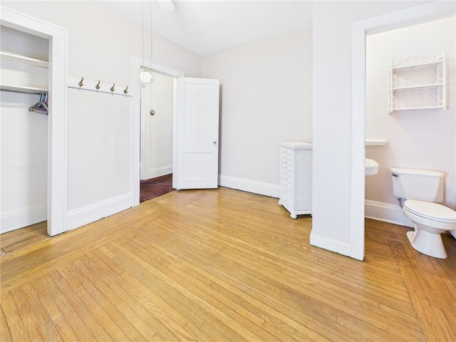 unfurnished bedroom featuring light wood-type flooring, baseboards, and a closet