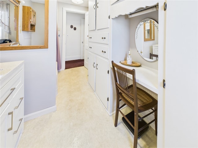 interior space featuring baseboards, white cabinetry, and light countertops