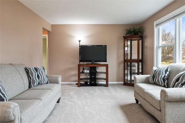 living area featuring baseboards and light carpet