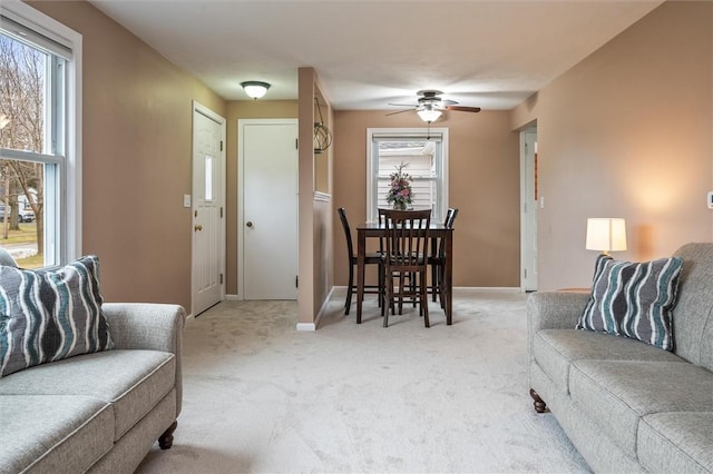 living area with light carpet, a healthy amount of sunlight, and baseboards