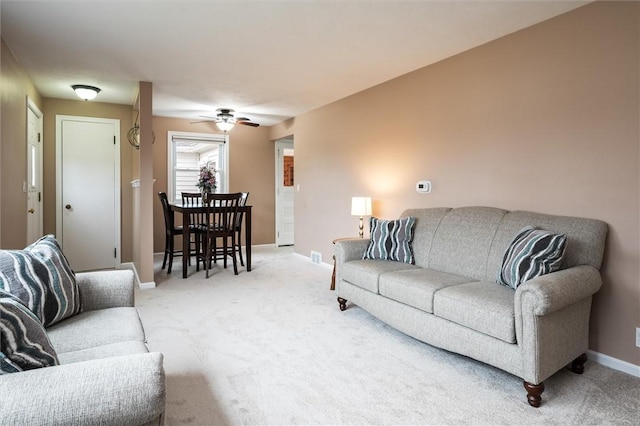 living area featuring light carpet, ceiling fan, and baseboards