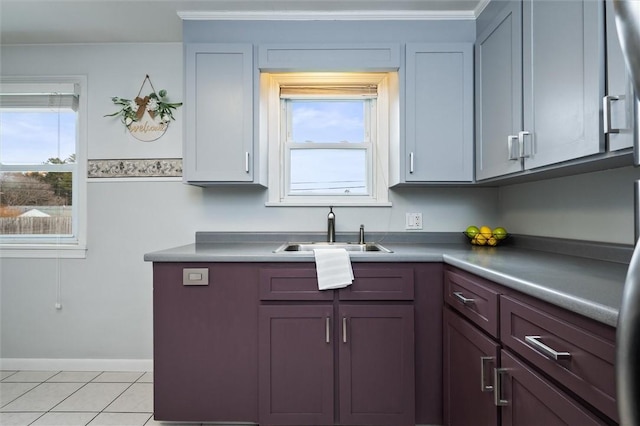 kitchen featuring light tile patterned flooring, baseboards, a wealth of natural light, and a sink