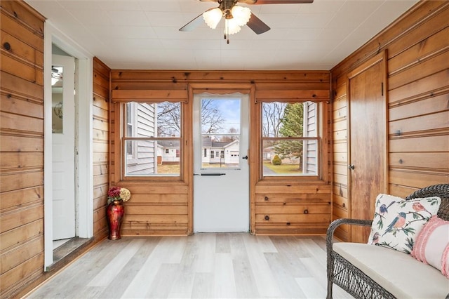 entryway featuring wooden walls, light wood-style flooring, and a ceiling fan