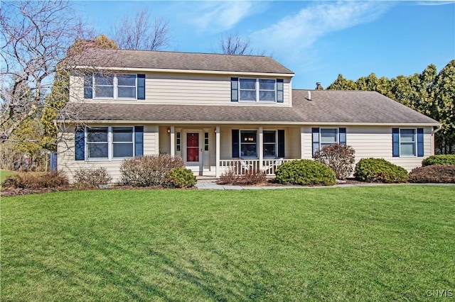 traditional-style home with covered porch, a shingled roof, and a front lawn