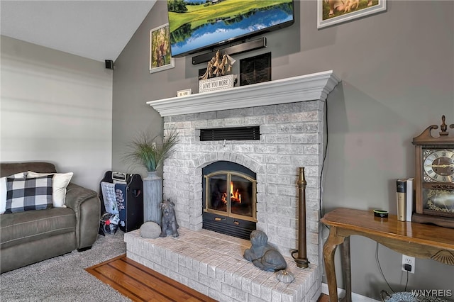 carpeted living area featuring visible vents, lofted ceiling, and a brick fireplace