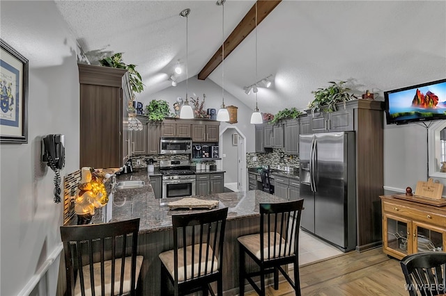 kitchen with gray cabinets, backsplash, appliances with stainless steel finishes, a peninsula, and vaulted ceiling with beams