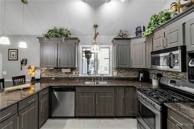 kitchen featuring backsplash, appliances with stainless steel finishes, a peninsula, light tile patterned flooring, and a sink