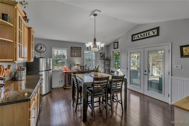 dining space featuring a wainscoted wall, dark wood-style floors, french doors, a chandelier, and vaulted ceiling