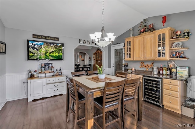 dining area with a wainscoted wall, dark wood-style floors, beverage cooler, and arched walkways