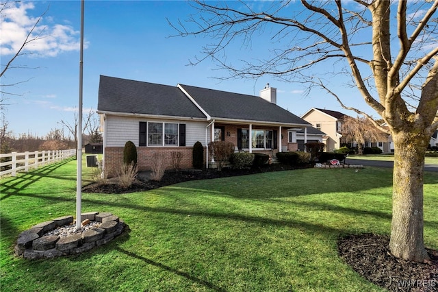 ranch-style home with brick siding, a front lawn, fence, an outdoor fire pit, and a chimney